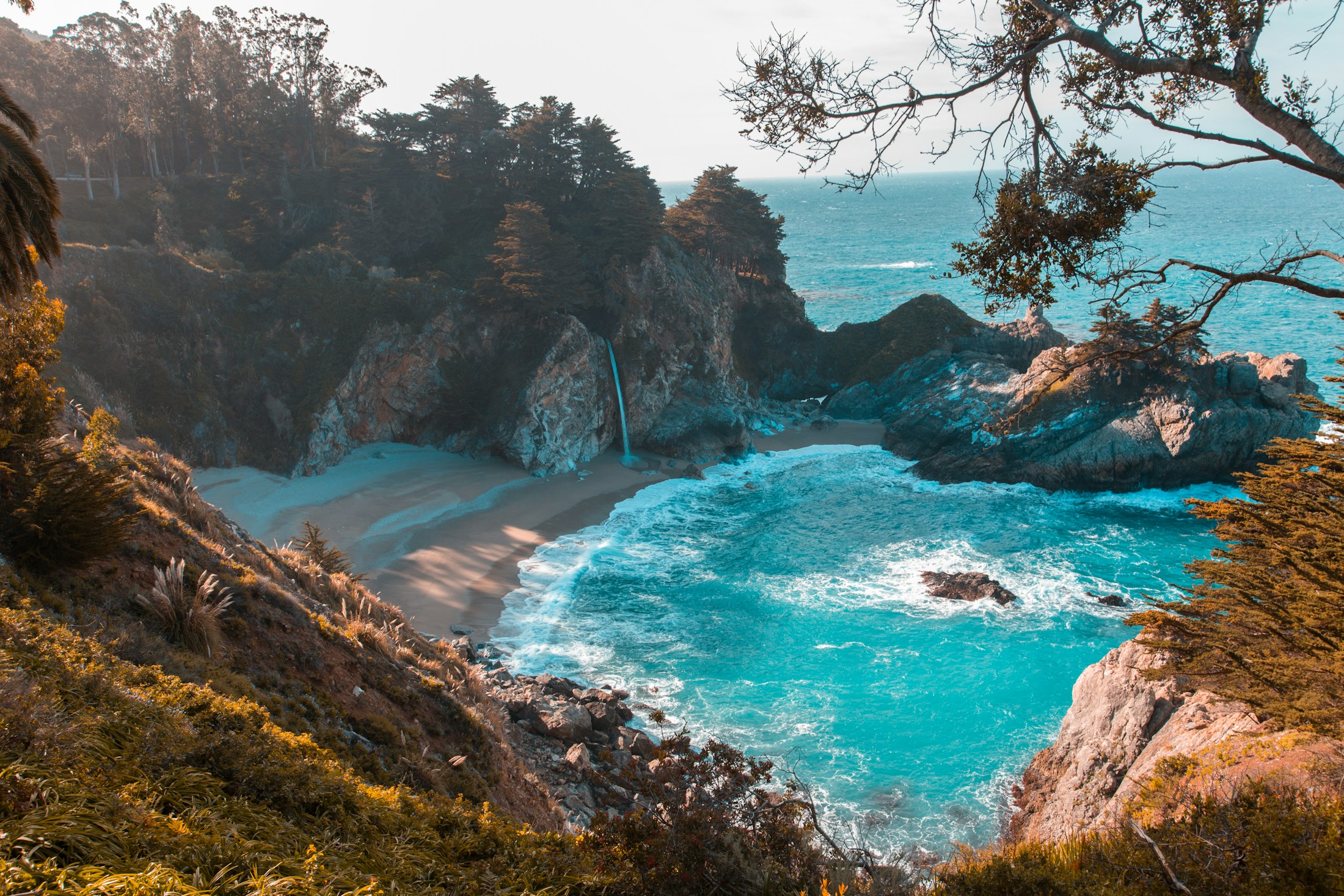 A quiet coastal cove, turquoise water and a waterfall meeting the ocean